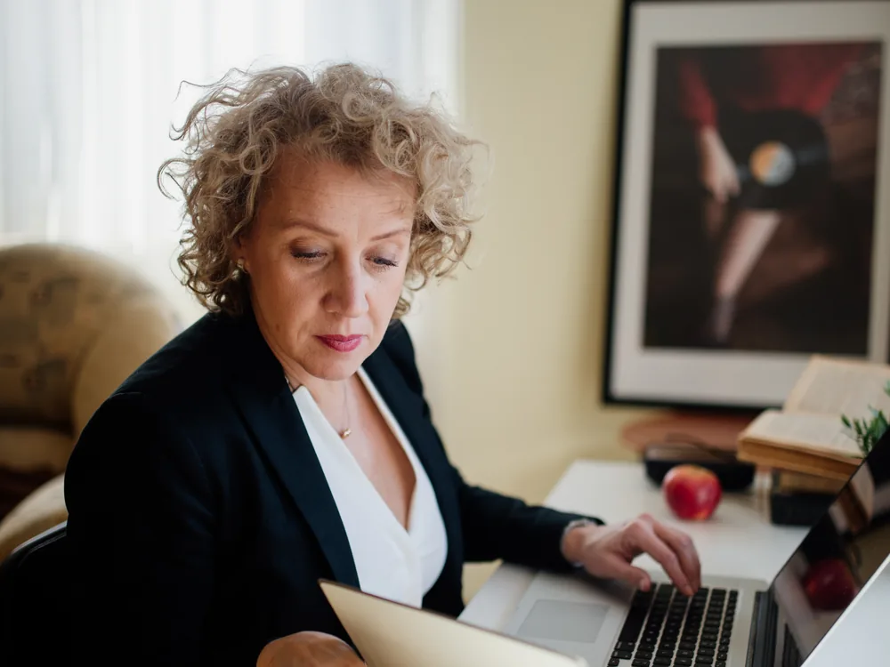 A professional working with a laptop and documents at a bright office desk