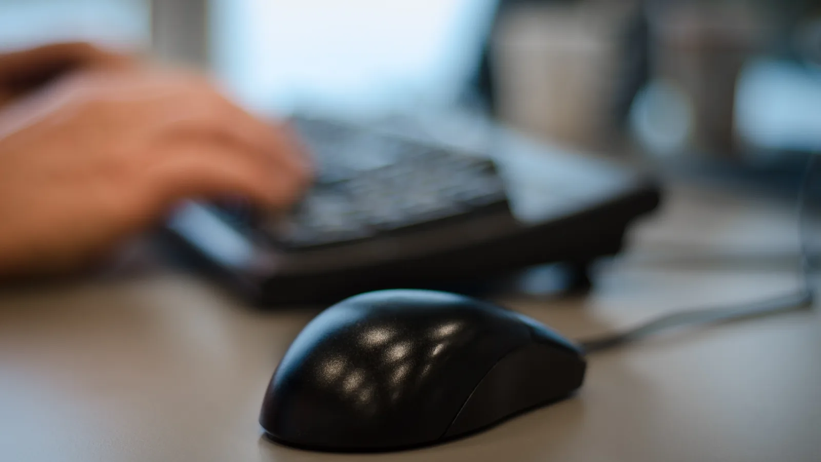 Hands working at an office desk with a notebook and pen